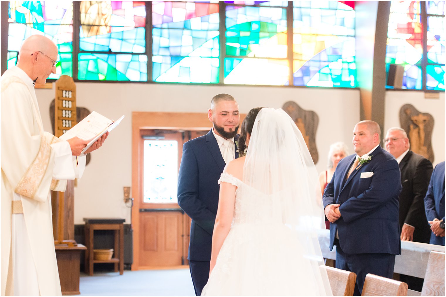 groom looks at bride during traditional wedding ceremony at Saint Matthew the Apostle church