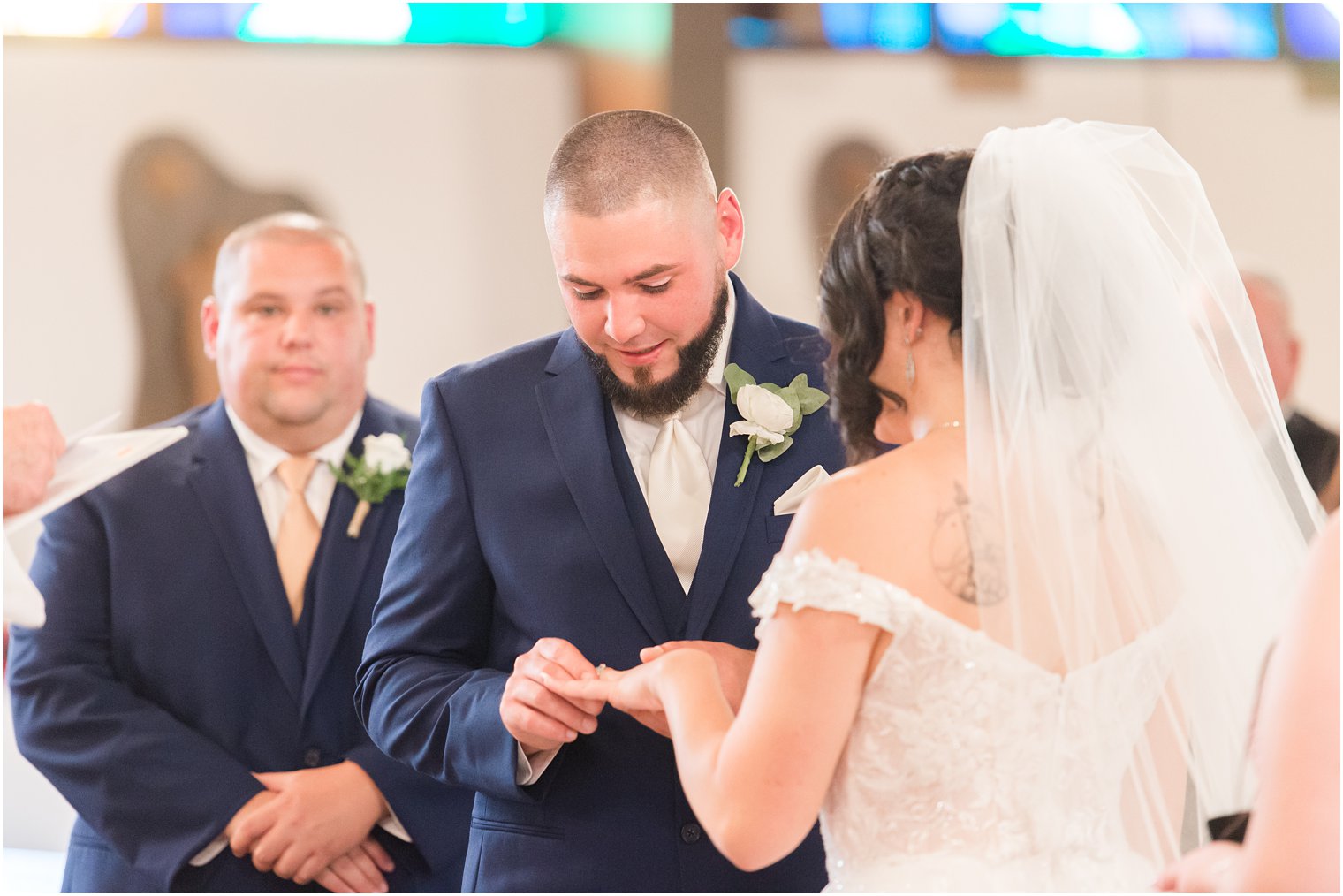 groom puts ring on bride's finger during traditional wedding ceremony at Saint Matthew the Apostle church