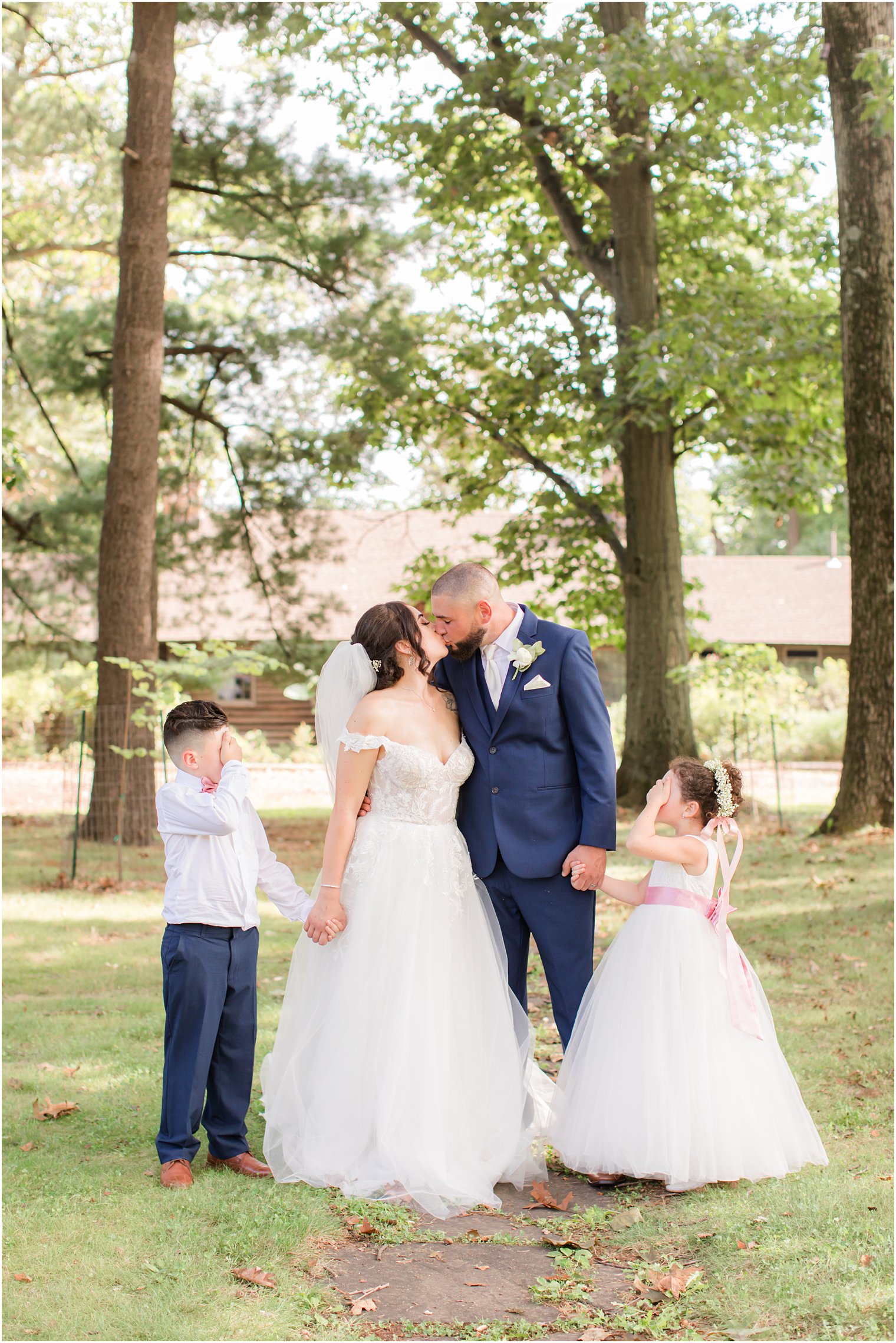 kids cover eyes while parents kiss on wedding day at Rutgers Gardens