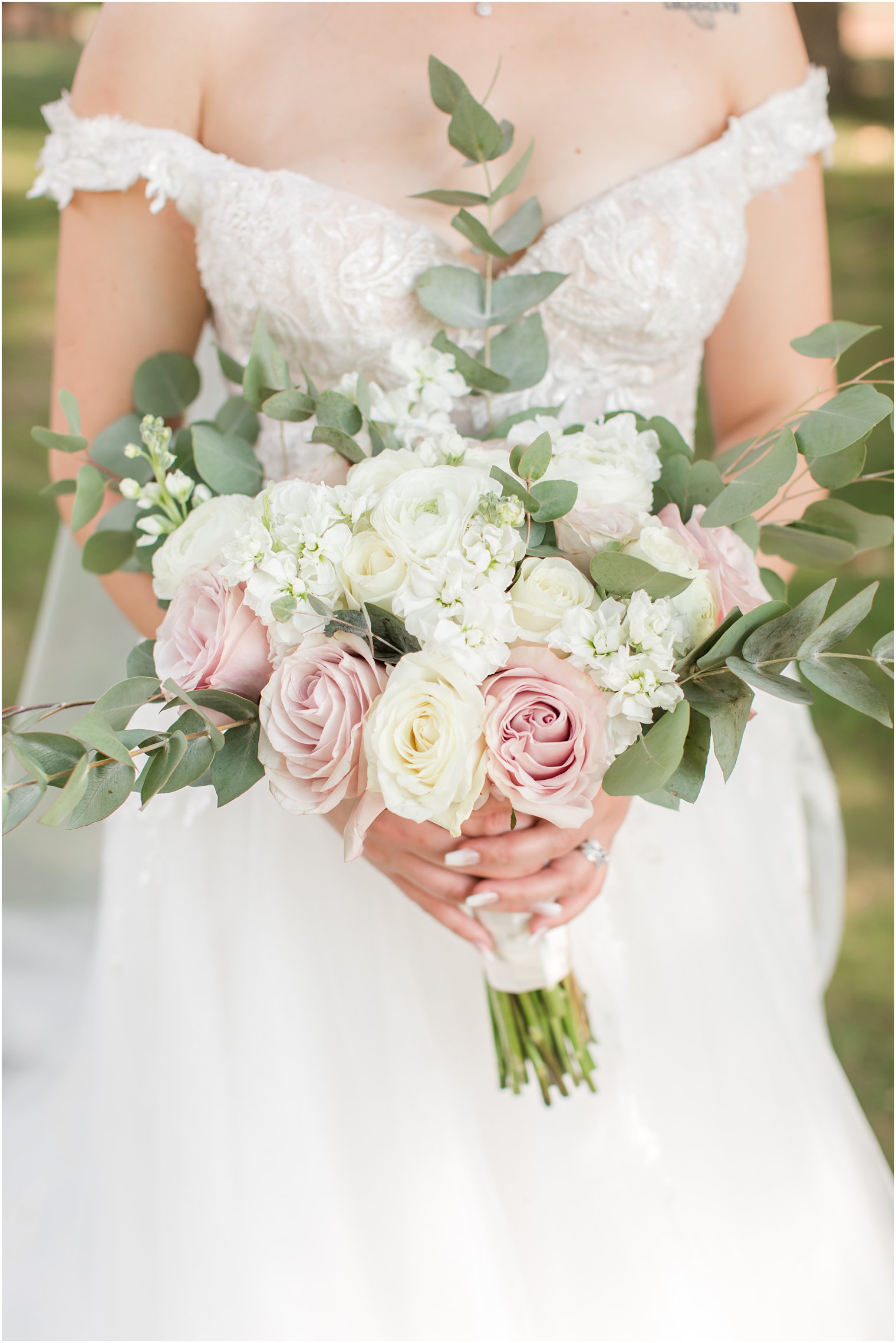 bride holds classic bouquet of pink and ivory roses with baby's breath 