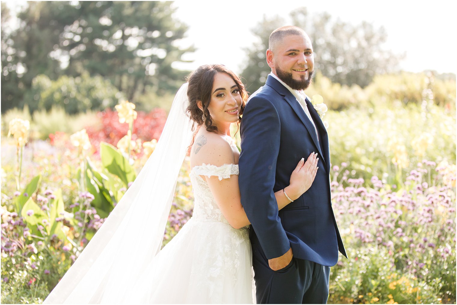 bride hugs groom from behind during NJ wedding photos 