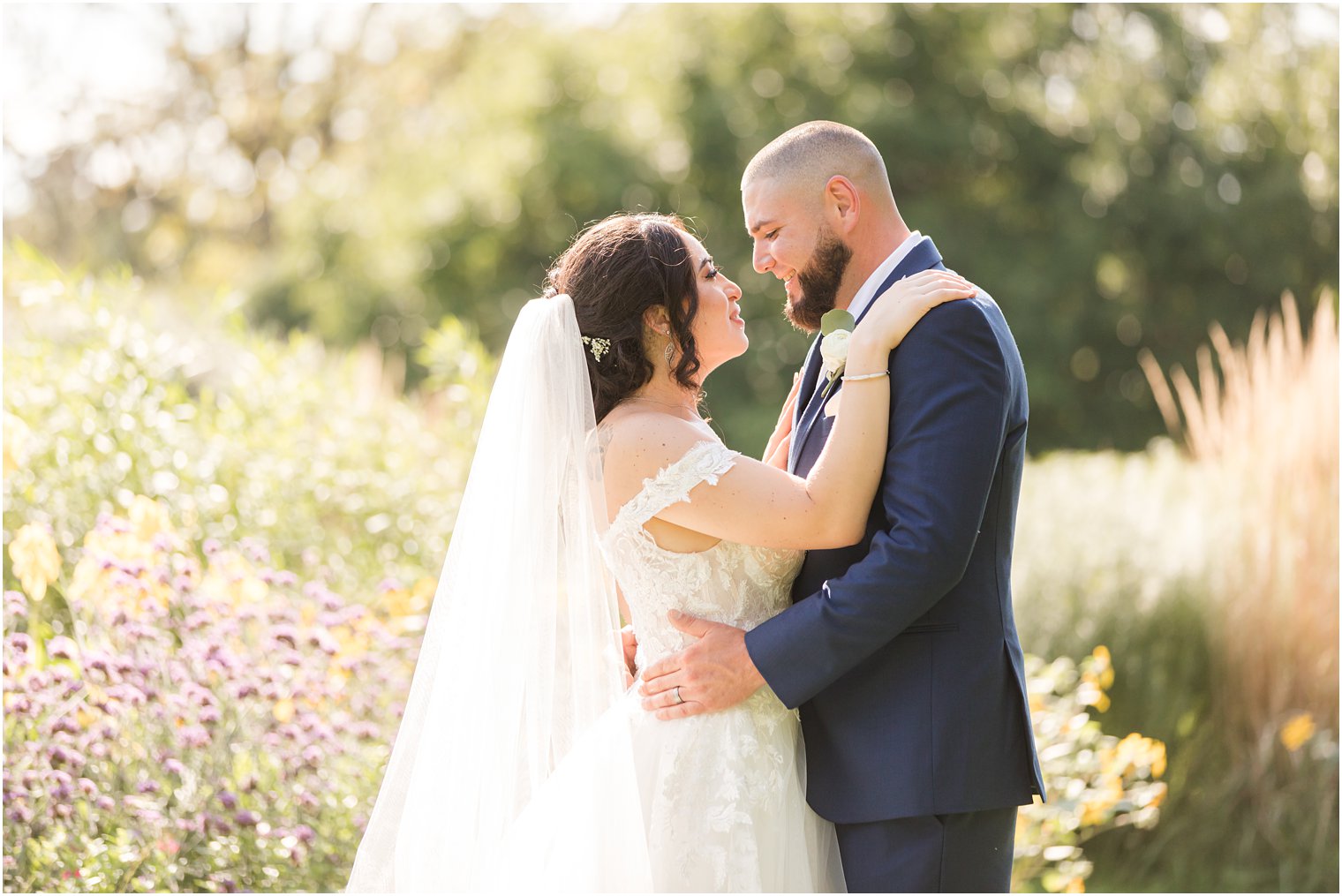 bride and groom smile together at Rutgers Gardens during wedding portraits 