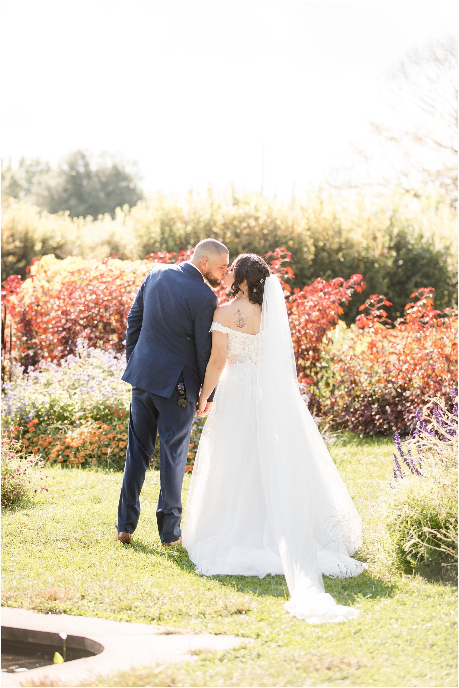 bride and groom hold hands kissing in Rutgers Gardens