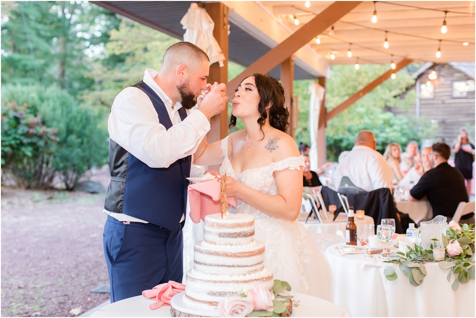 newlyweds feed each other cake during NJ wedding reception at park 