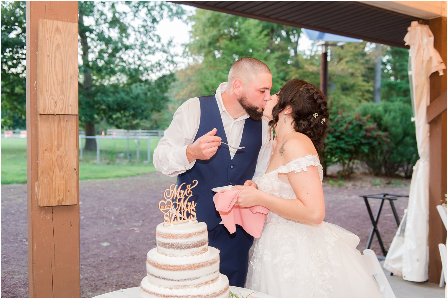 couple kisses during cake cutting at Rutgers Gardens