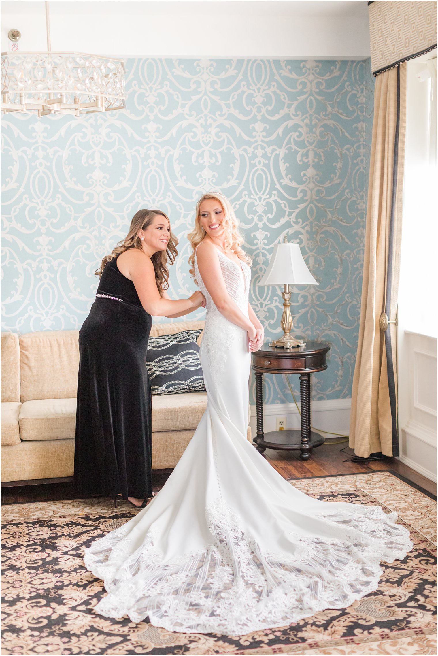bridesmaid helps bride with buttons on her wedding gown at the Molly Pitcher Inn