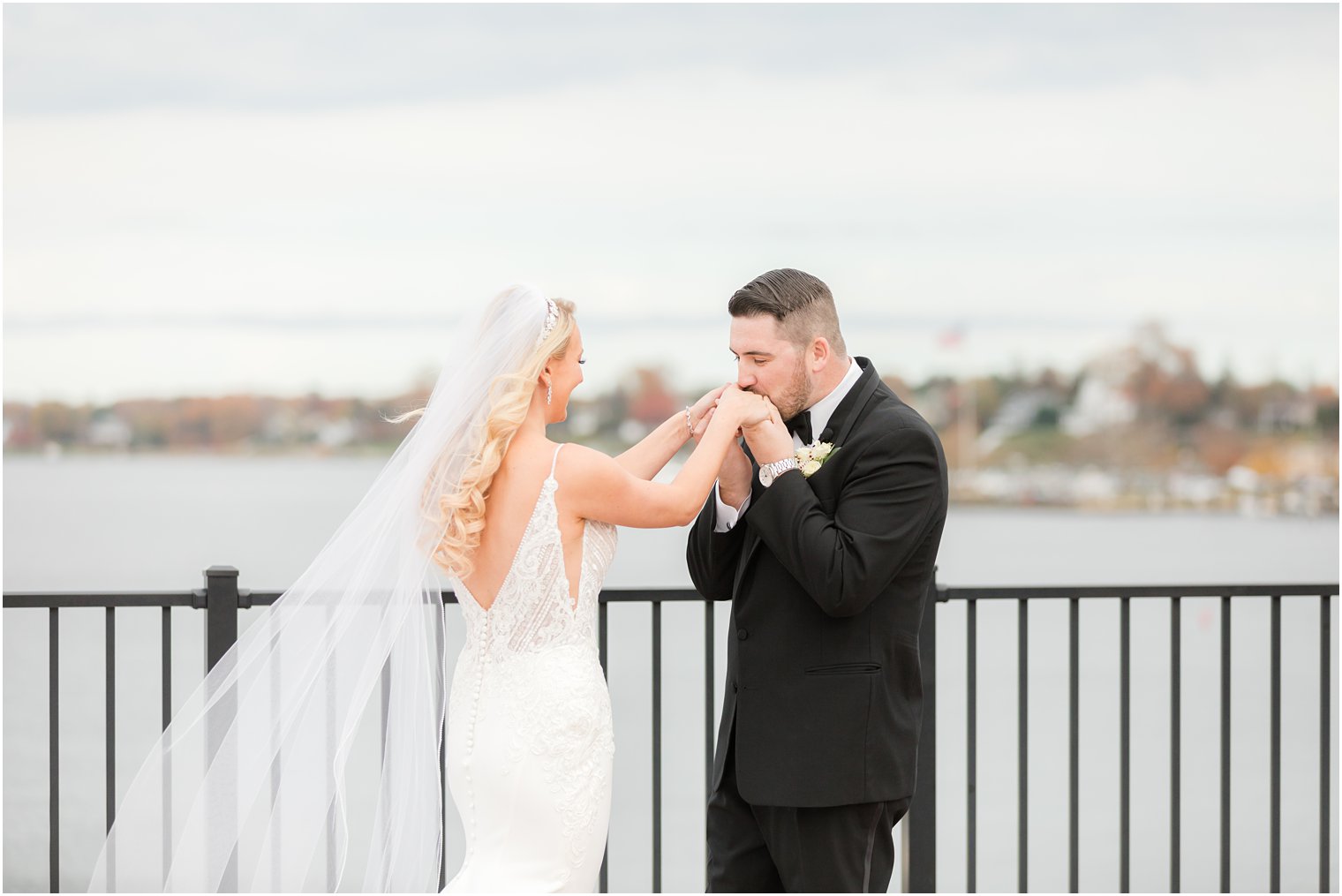 groom kisses bride's hands during first look overlooking the water in Red Bank NJ