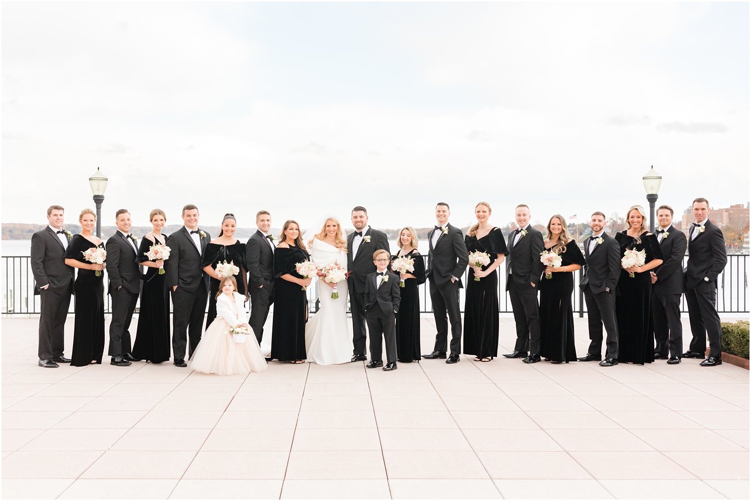 bride and groom pose with wedding party in all black outside the Molly Pitcher Inn