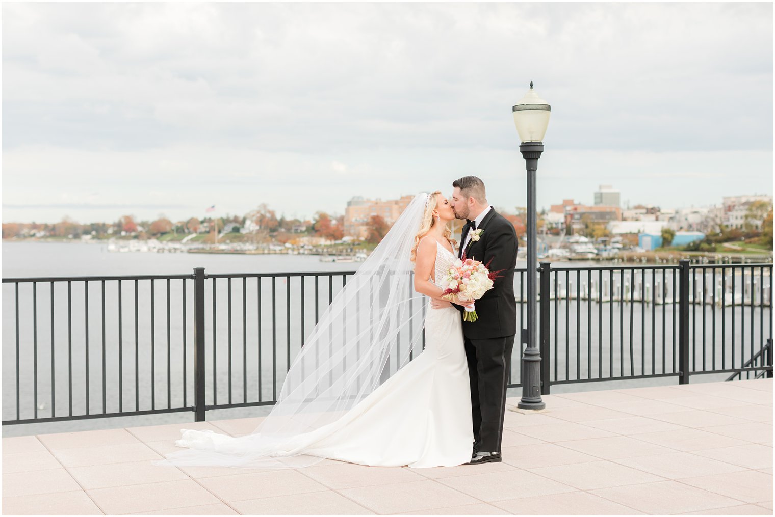 newlyweds kiss on patio at the Molly Pitcher Inn overlooking the Red Bank marina 