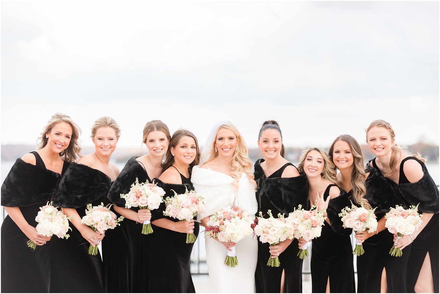 bride stands with bridesmaids in black dresses and wraps in Red Bank NJ