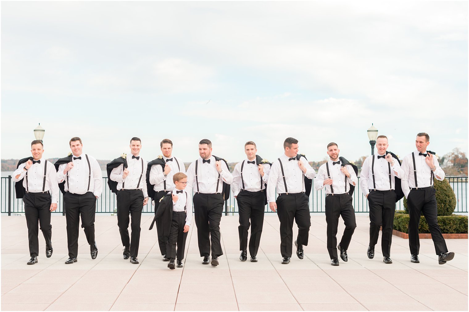 groom walks with groomsmen and ring bearer outside the Molly Pitcher Inn with jackets over their shoulders