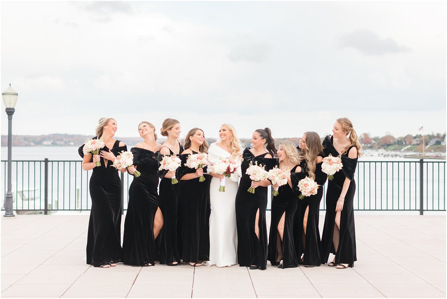 bride smiles at bridesmaids in all black dresses on the patio at the Molly Pitcher Inn