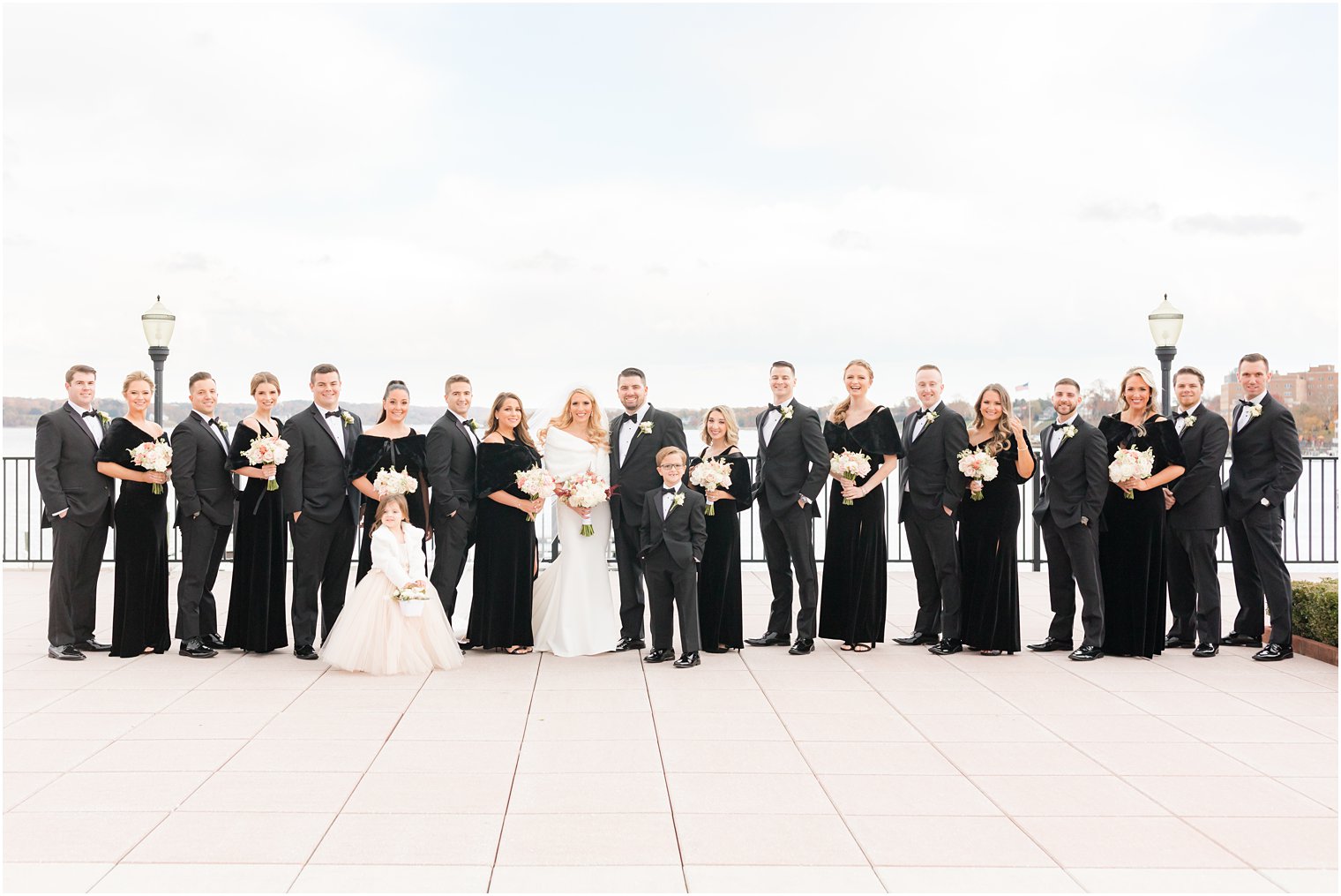 bride and groom stand with wedding party in all black on the patio at the Molly Pitcher Inn