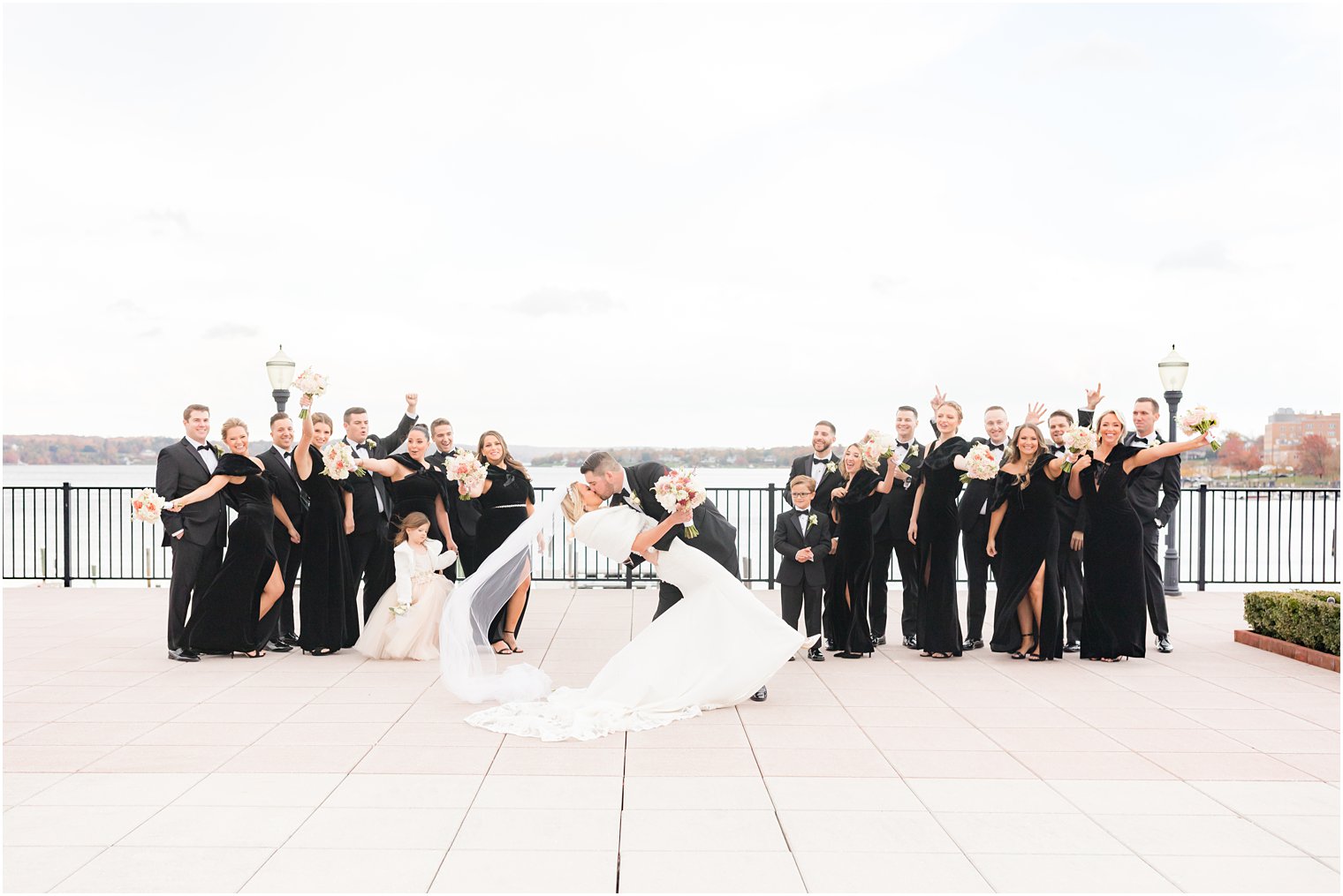 groom kisses bride dipping her on the patio of the Molly Pitcher Inn while wedding party cheers around them