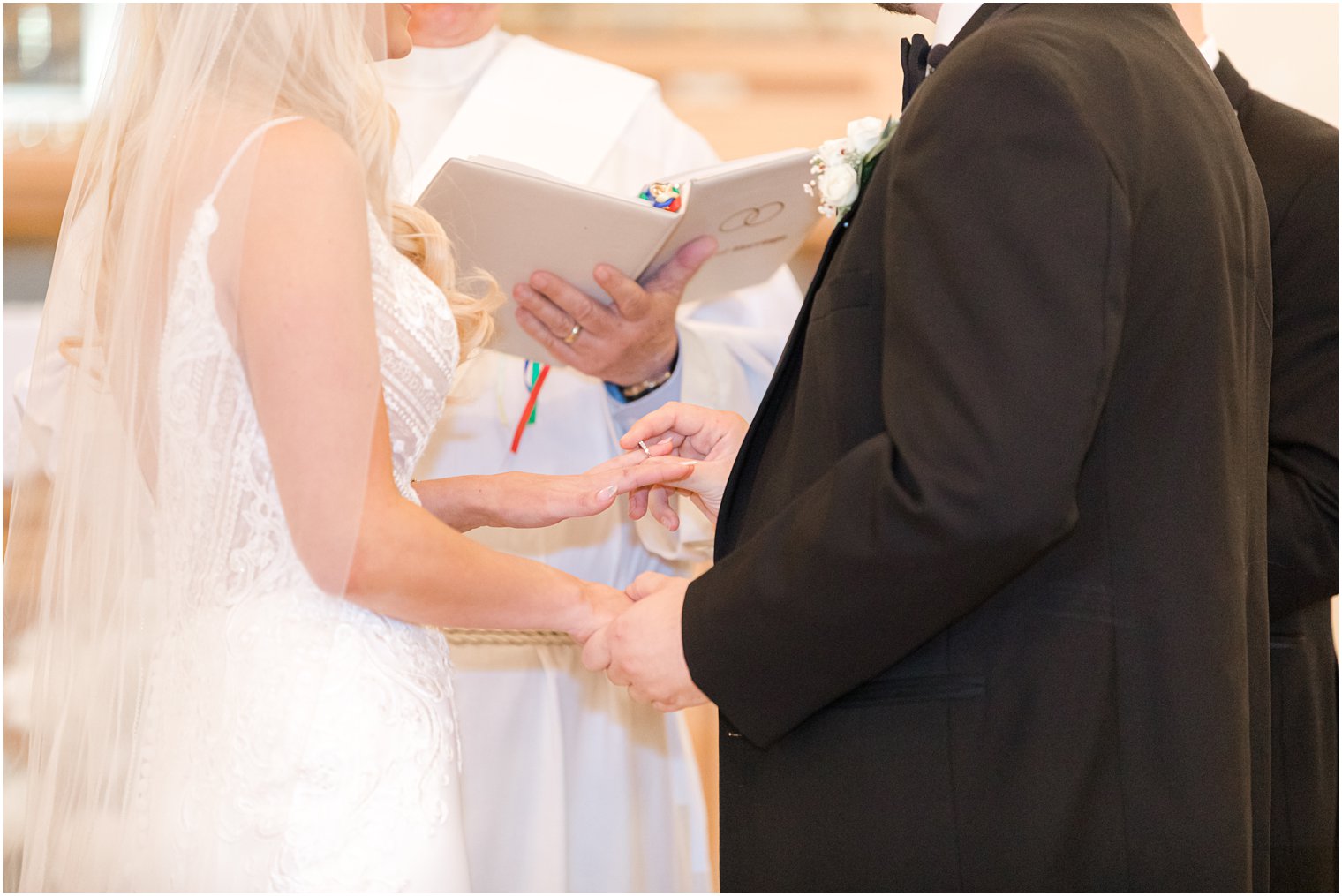 groom slides ring on bride's finger during wedding ceremony 