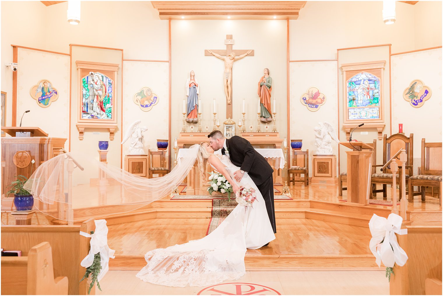groom kisses bride with her veil floating in New Jersey church 