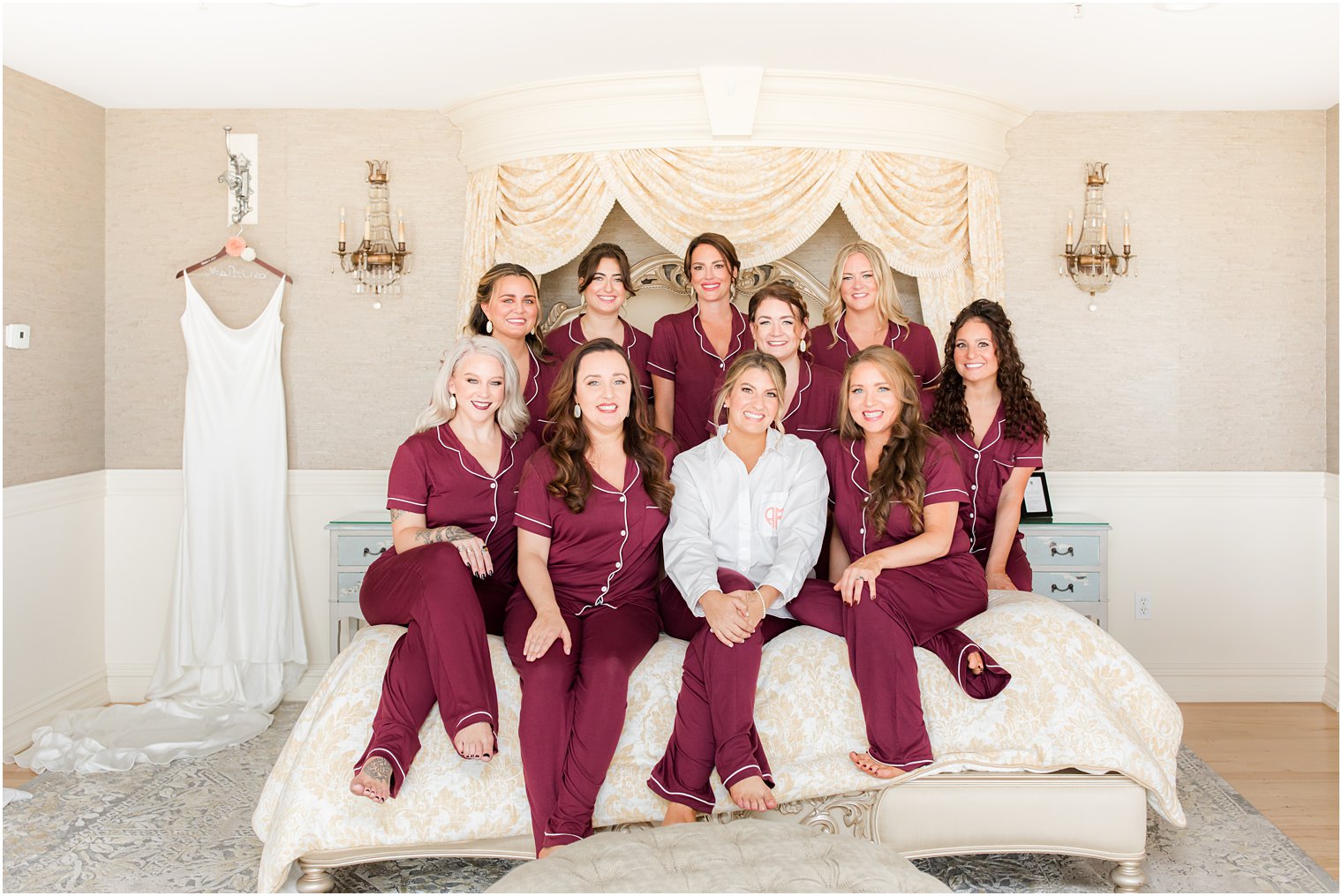bride poses with bridesmaids in matching burgundy pajamas on bed at Bonnet Island Estate