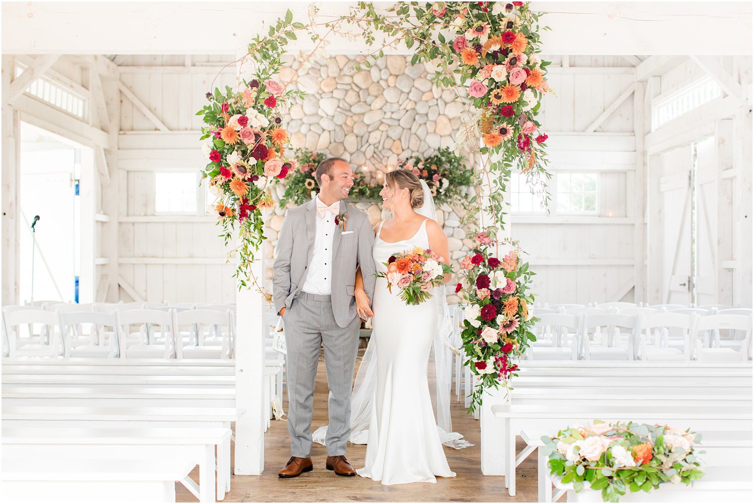 bride and groom hold hands by floral arch at Bonnet Island Estate