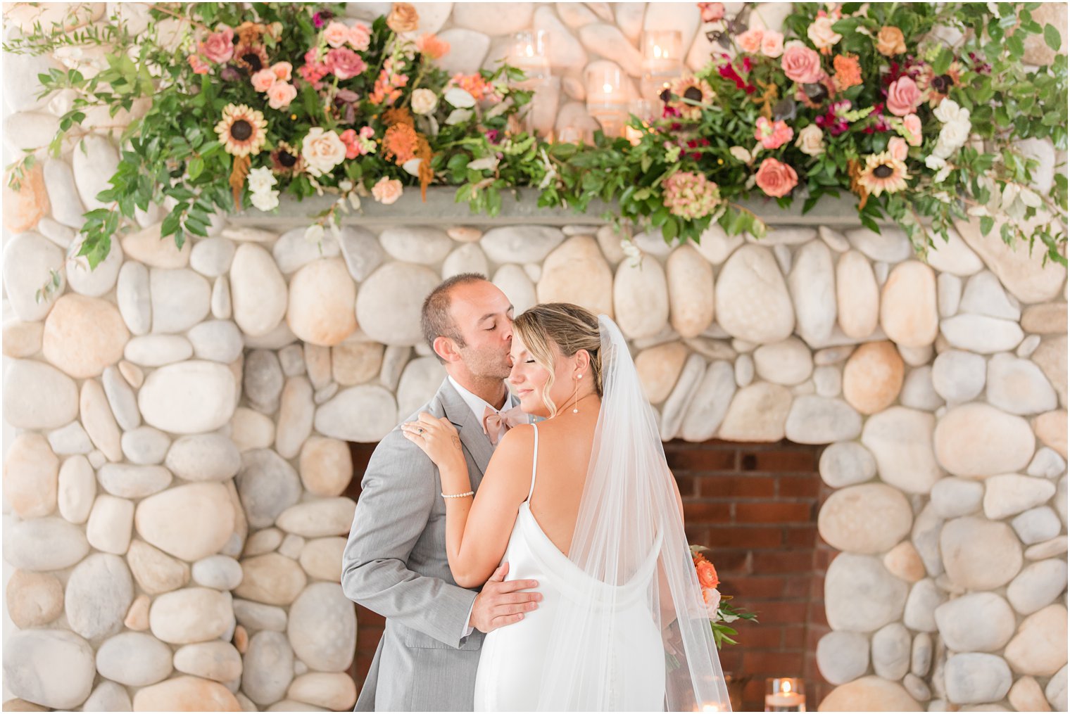 groom kisses bride's forehead by fireplace at Bonnet Island Estate