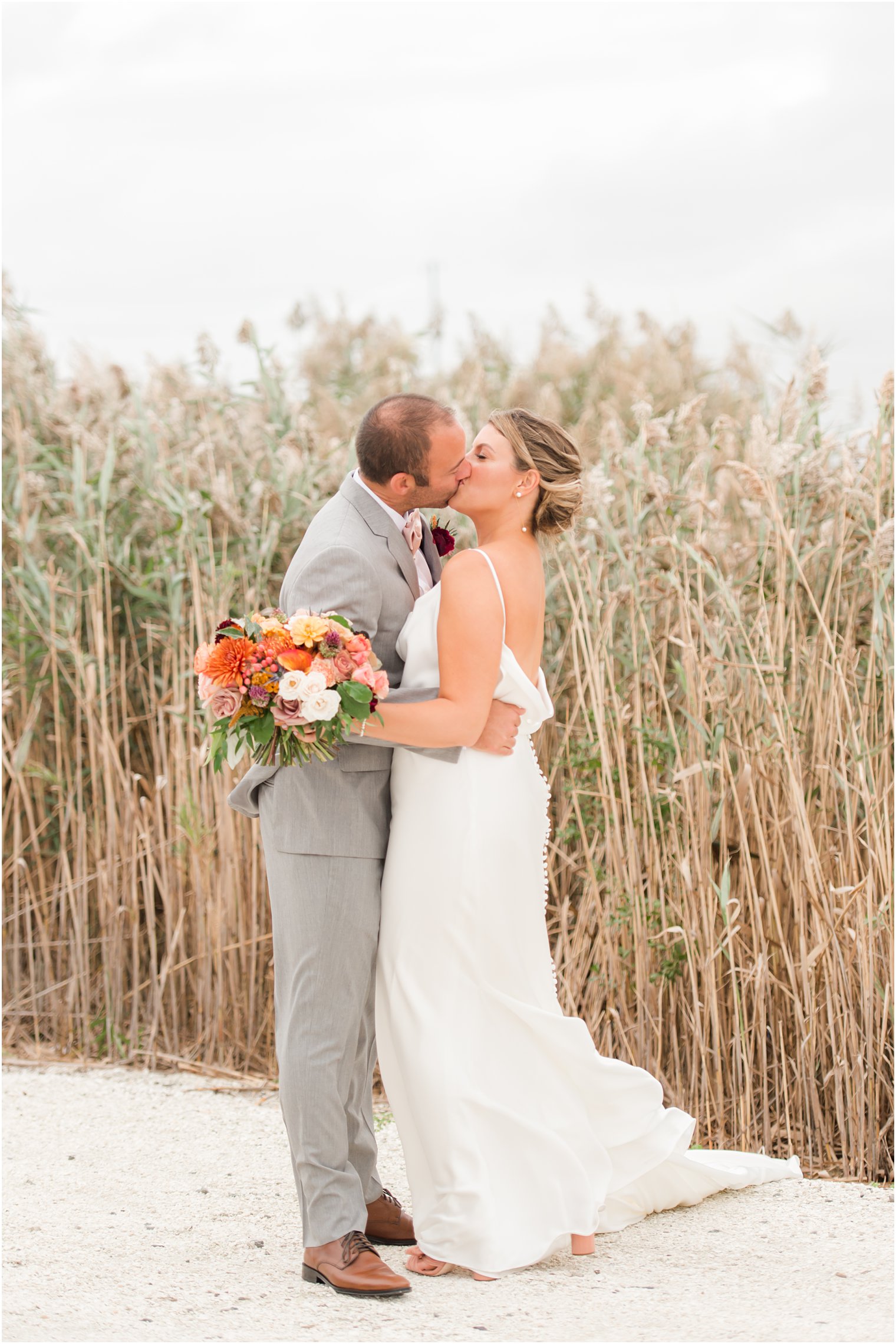 bride and groom kiss on Manahawkin NJ beach during fall wedding day