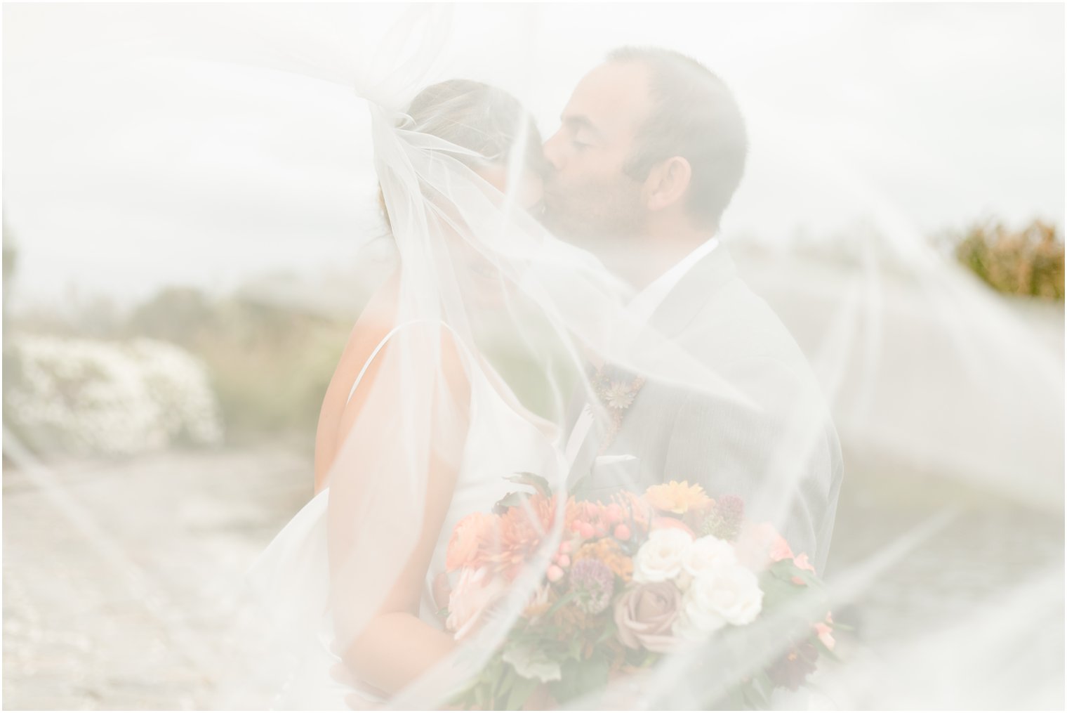 groom kisses bride under veil during Bonnet Island Estate wedding portraits 