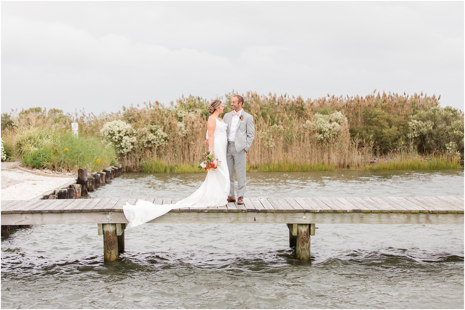 newlyweds stand on dock in Manahawkin NJ during fall wedding portraits 