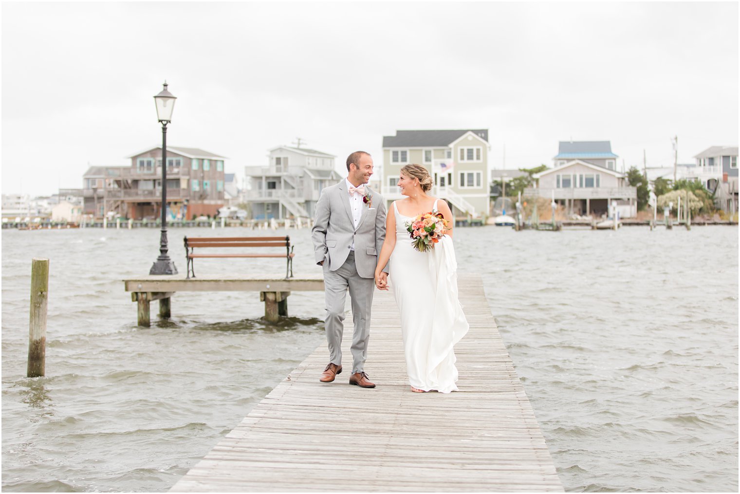 bride and groom hold hands walking down dock outside Bonnet Island Estate