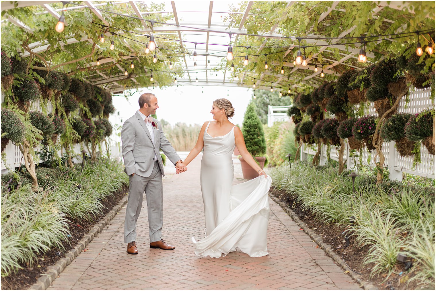 bride and groom hold hands under garden lights at Bonnet Island Estate