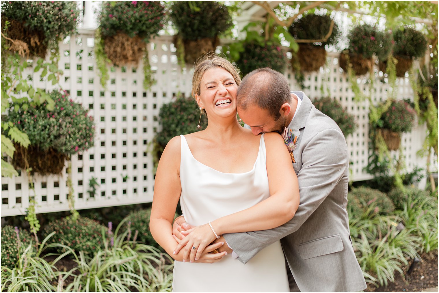 groom kisses bride's shoulder during portraits in gardens of Bonnet Island Estate
