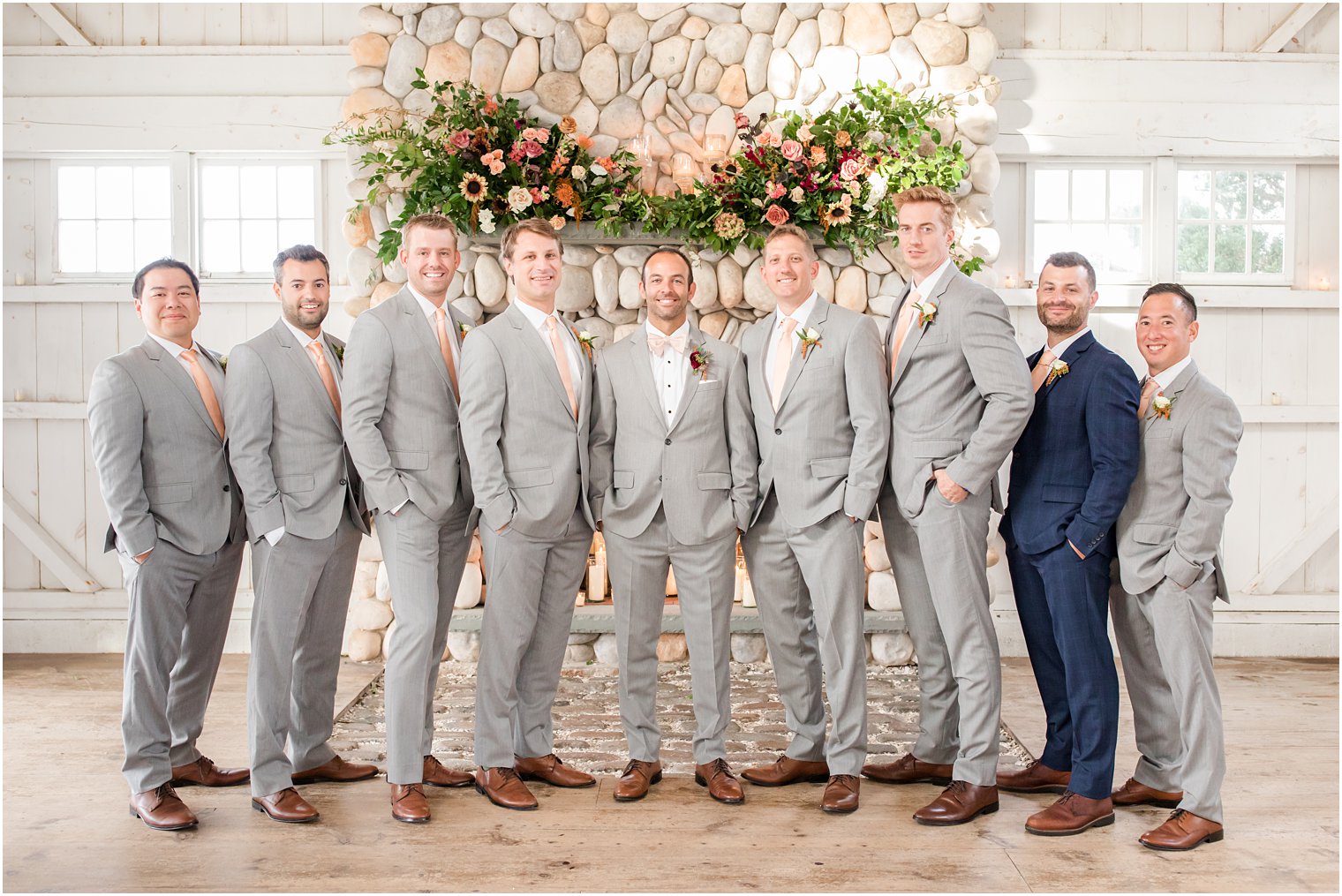 groom stands with groomsmen in grey suits at Bonnet Island Estate fireplace