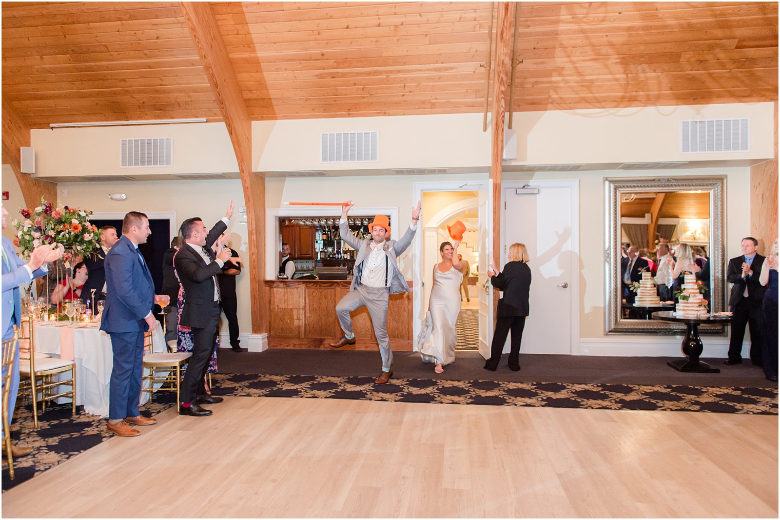 newlyweds run into wedding reception with orange top hats