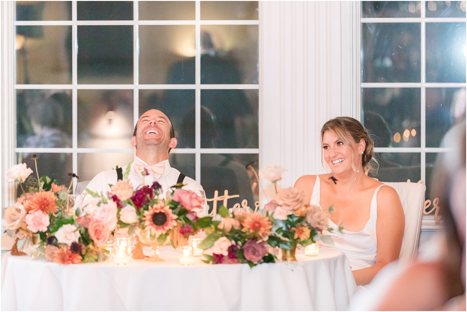 newlyweds laugh together during NJ wedding reception 
