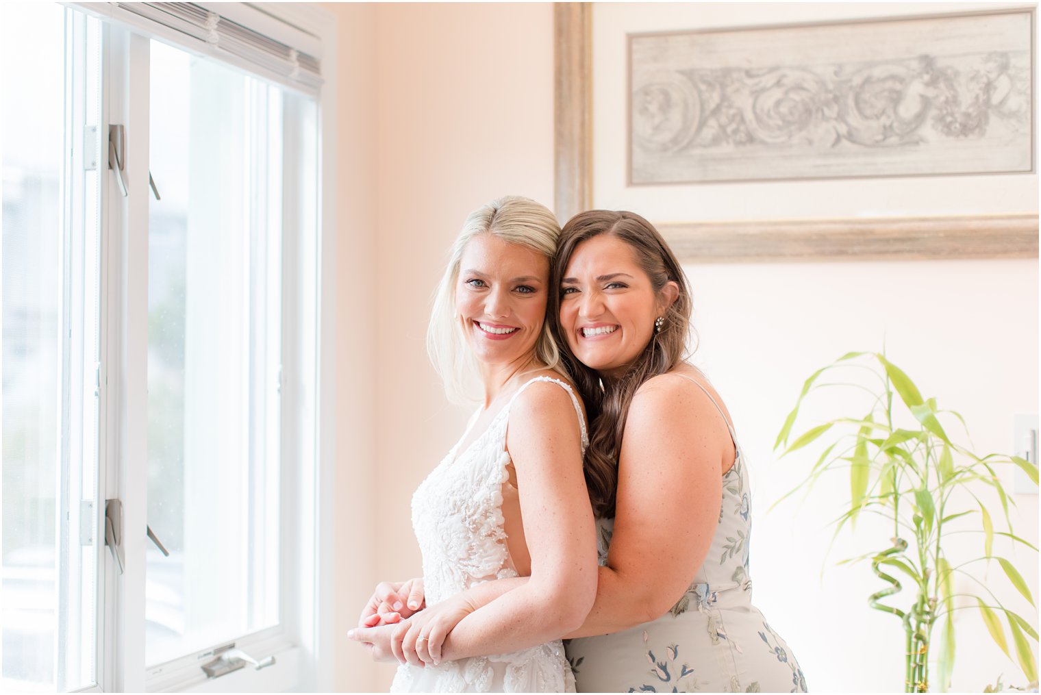 bridesmaid hugs bride on wedding morning while preparing 