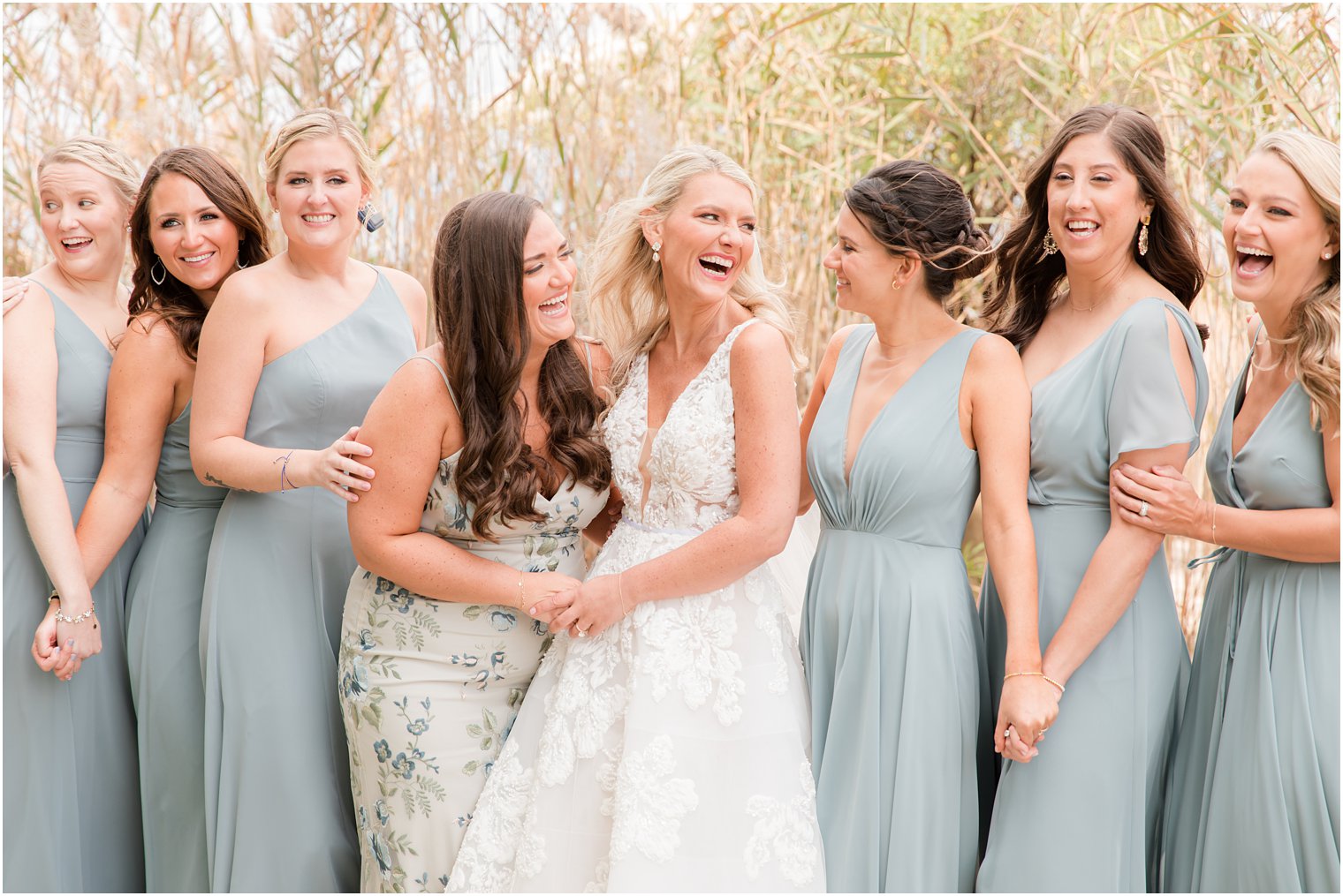 bride and bridesmaids laugh on beach before wedding day 