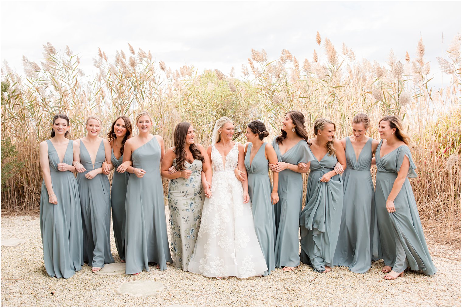 bride and bridesmaids walk on beach together before fall wedding day