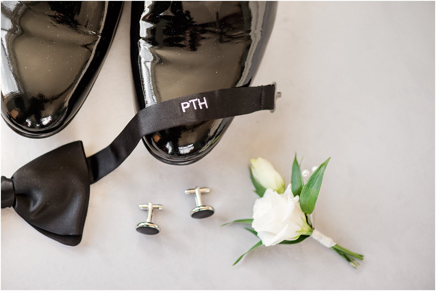 groom's custom bowtie rests on black shoes for beach wedding 