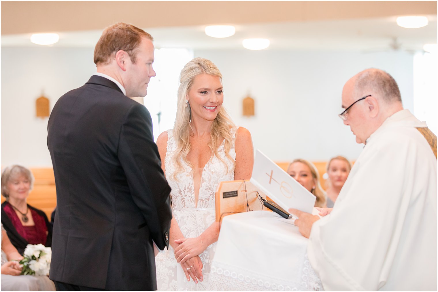 bride and groom smile at priest during traditional church wedding in New Jersey