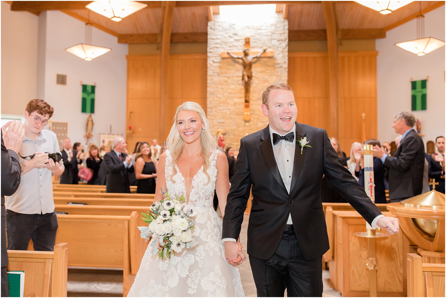 newlyweds walk up aisle holding hands after traditional church wedding in New Jersey