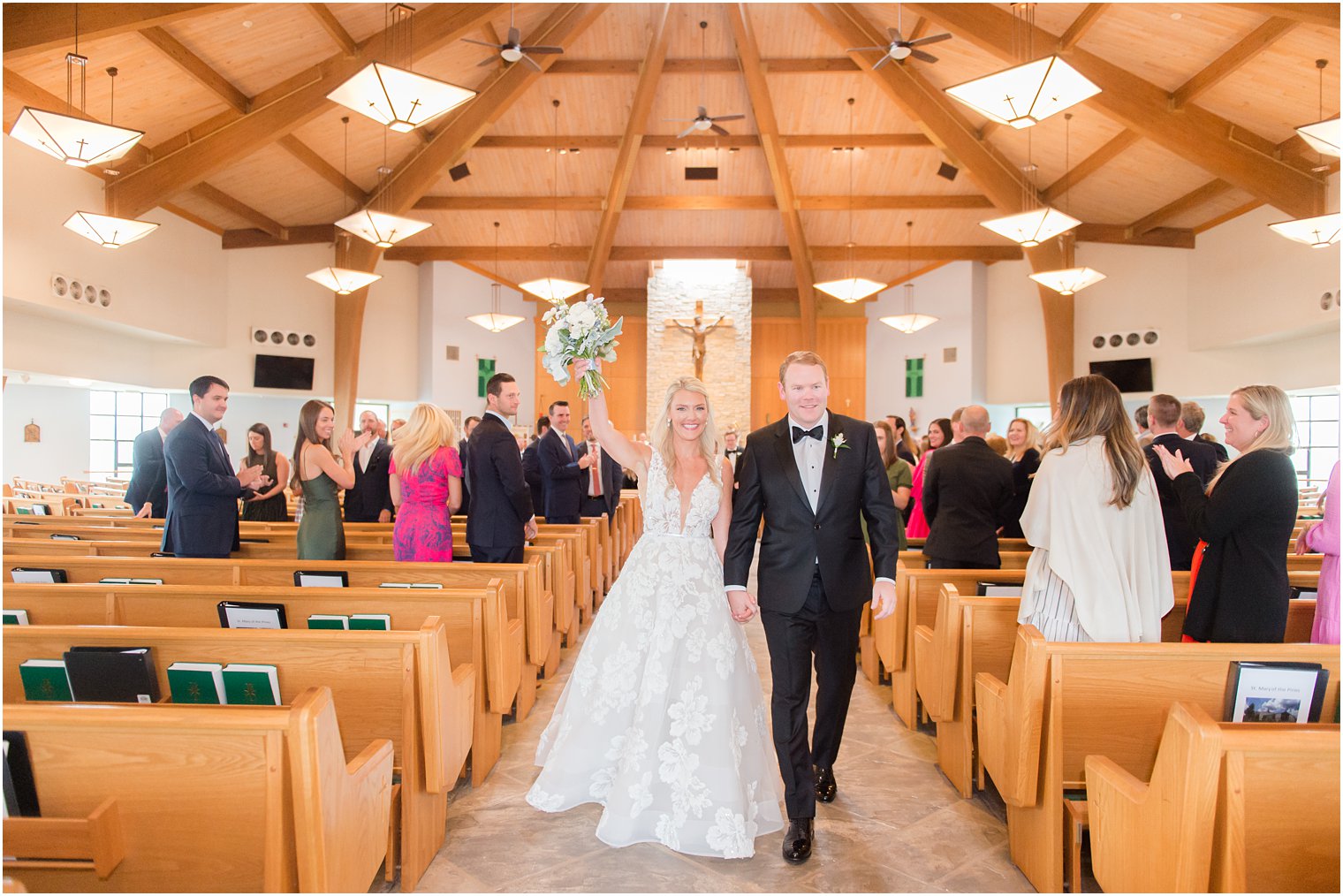 bride cheers walking up aisle in church after traditional church wedding in New Jersey