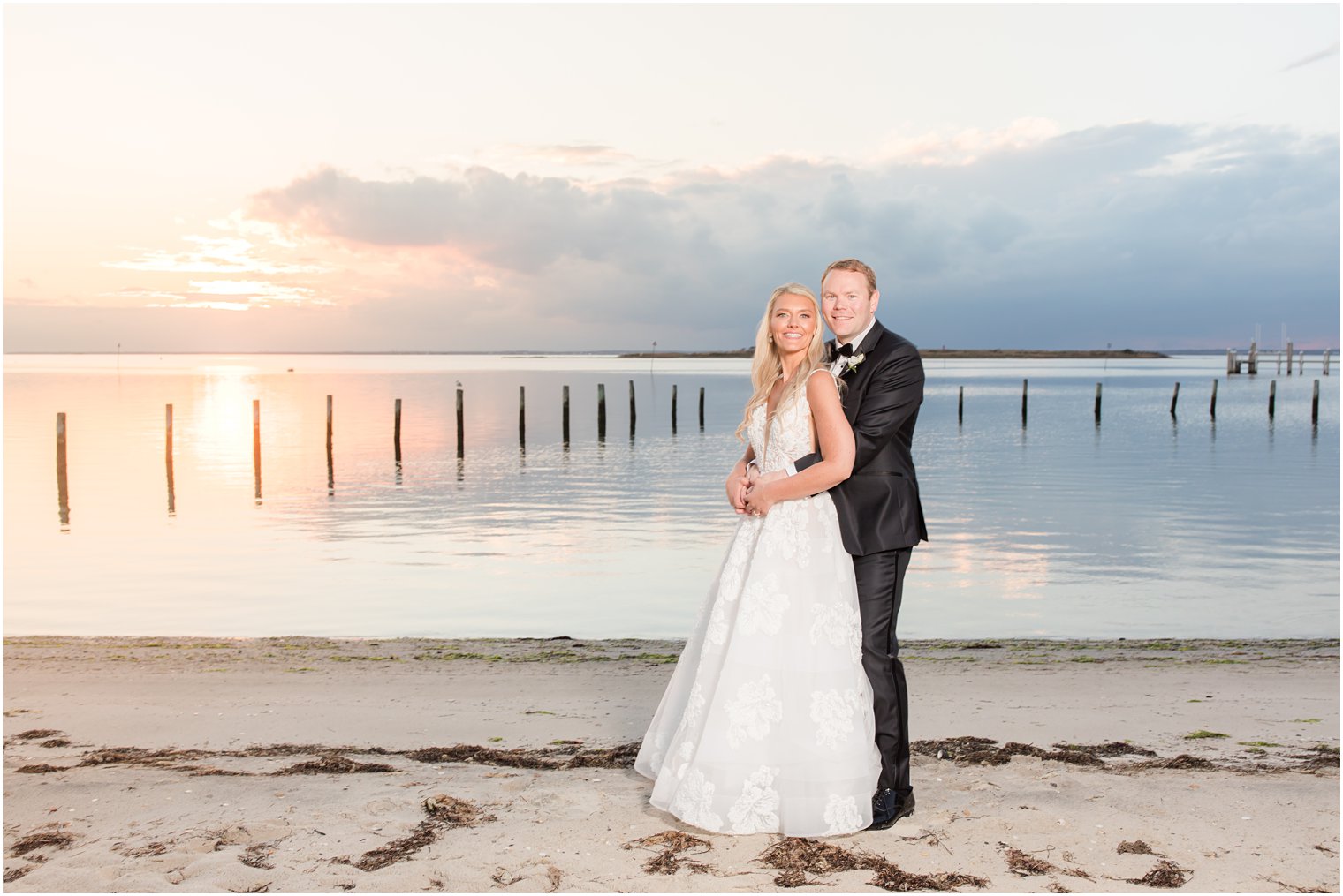 groom hugs bride on Brant Beach at sunset 