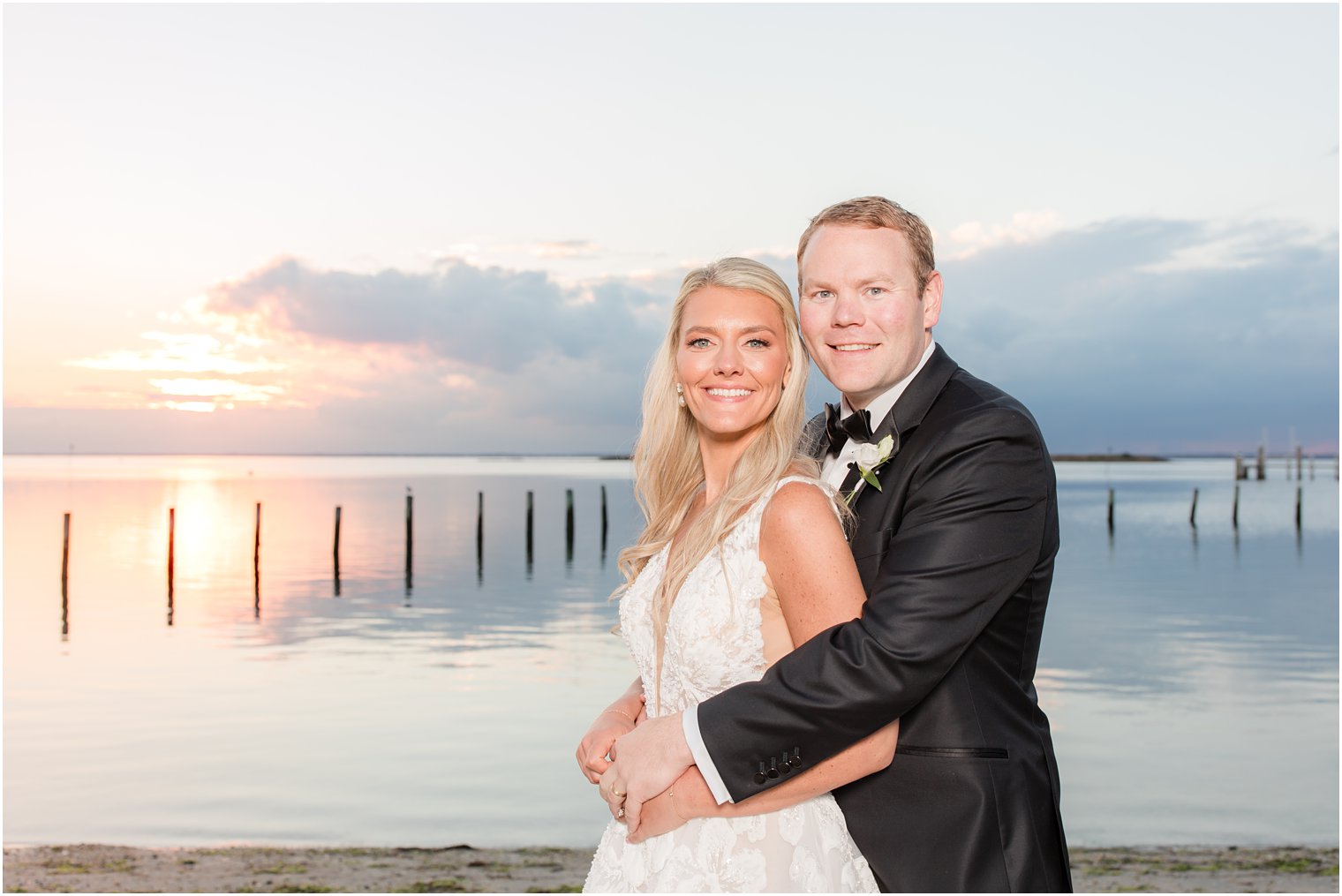 groom hugs bride on beach in New Jersey during wedding portraits 