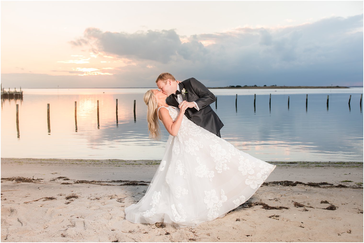 groom dips bride kissing her on fall beach wedding day