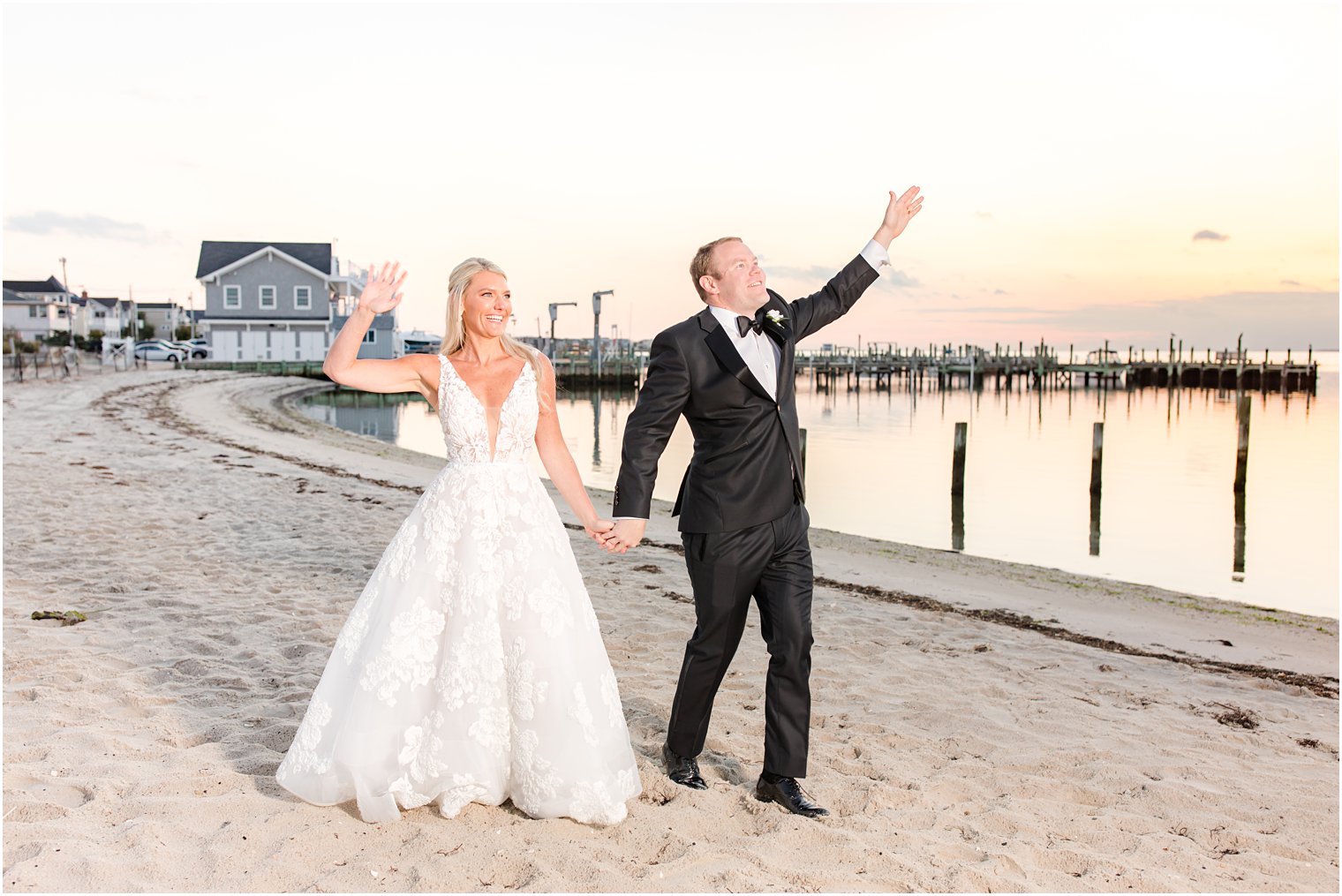 bride and groom wave on Brant Beach at sunset