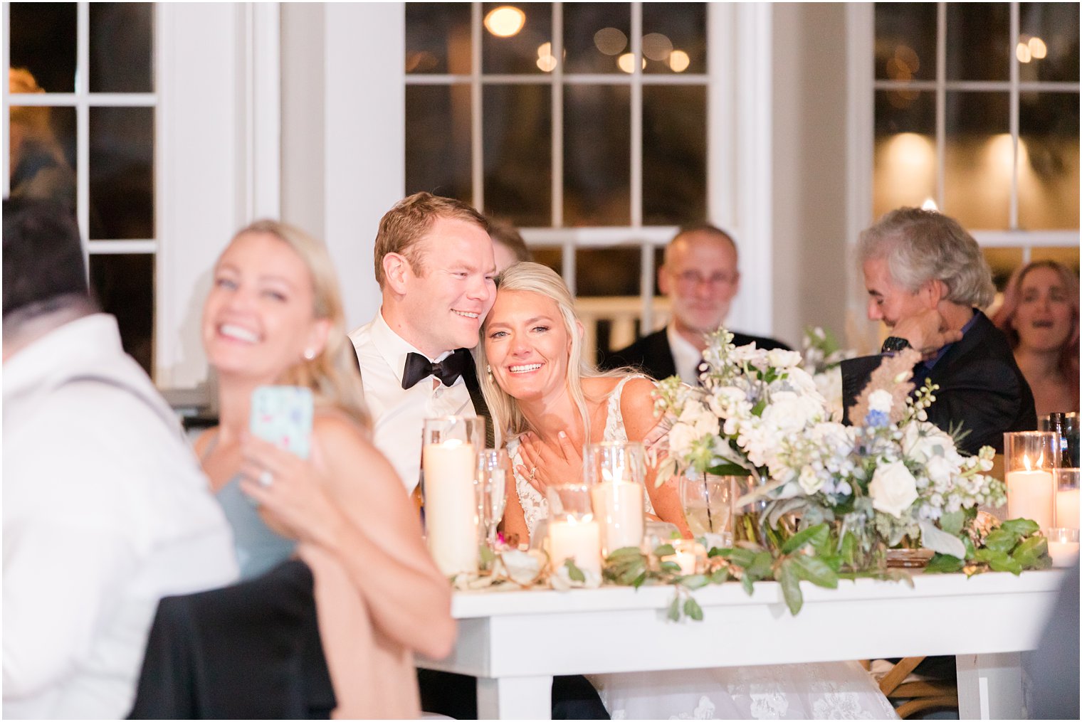 bride and groom snuggle together during speeches at Long Beach NJ wedding reception 