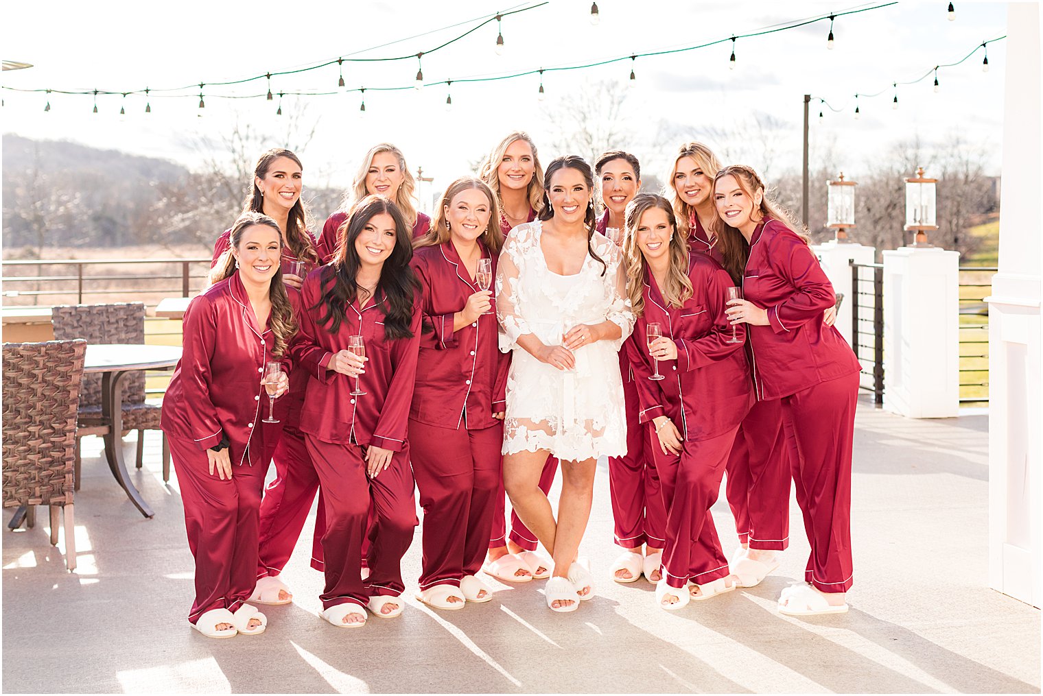 bridesmaids hug bride in matching red pajamas on patio at Bear Brook Valley