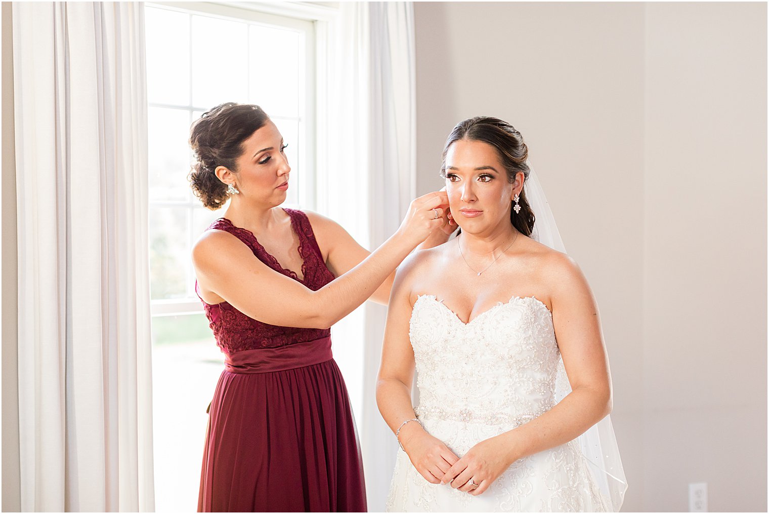 bridesmaid adjusts bride's earrings before Bear Brook Valley wedding