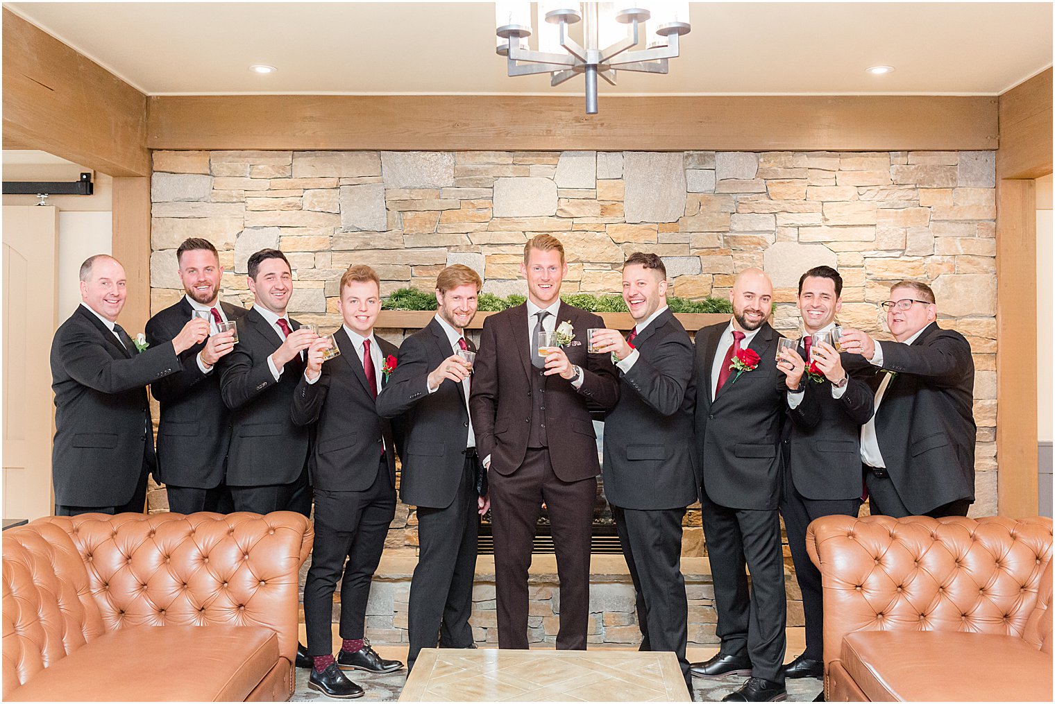 groom and groomsmen stand together by brick fireplace at Bear Brook Valley