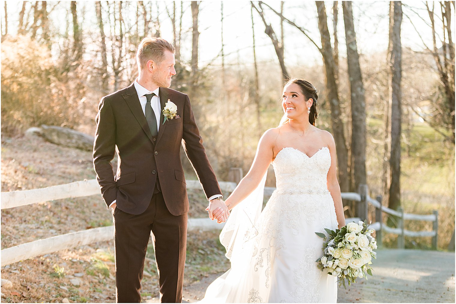 bride and groom hold hands walking over bridge