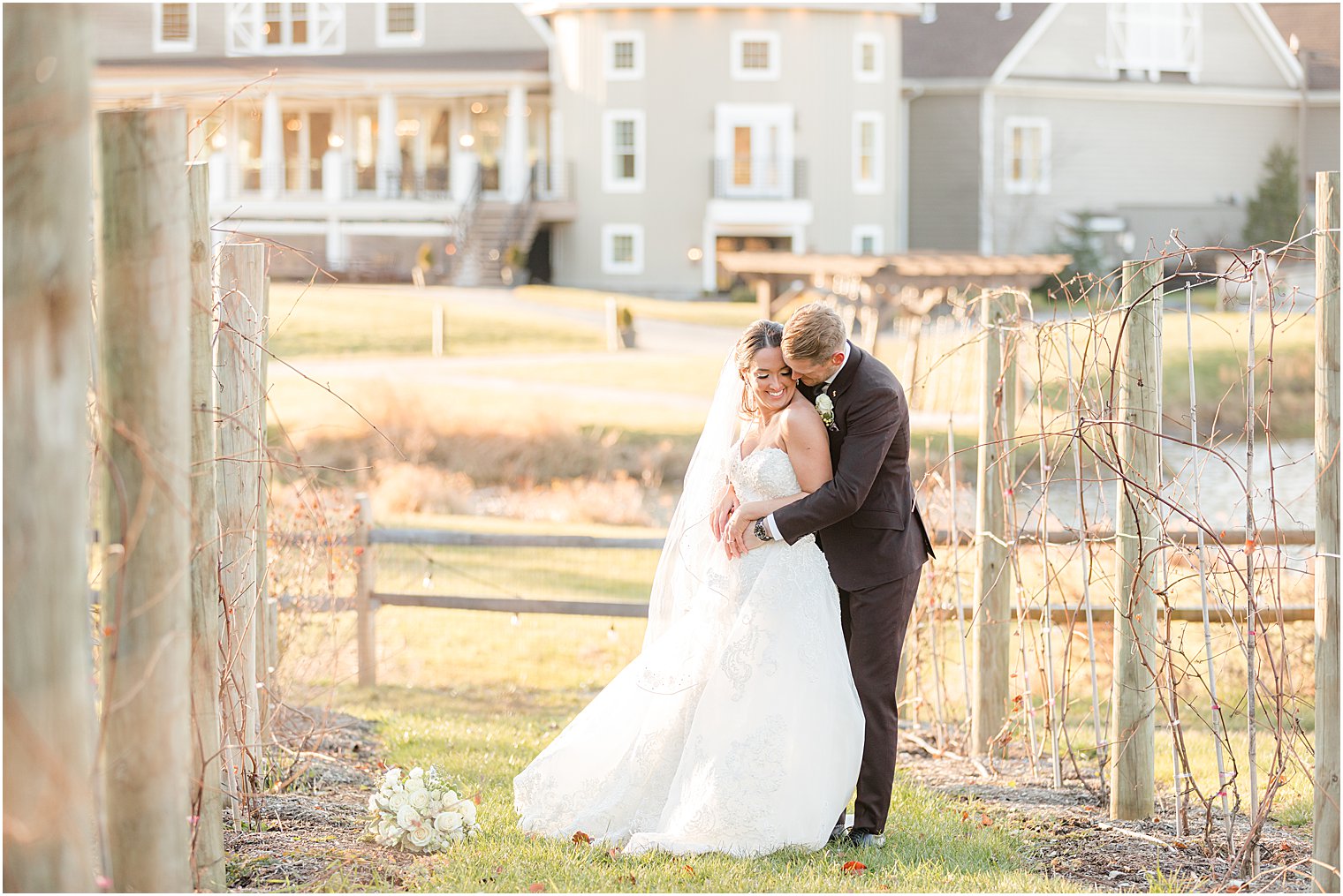 groom hugs bride from behind kissing her shoulder