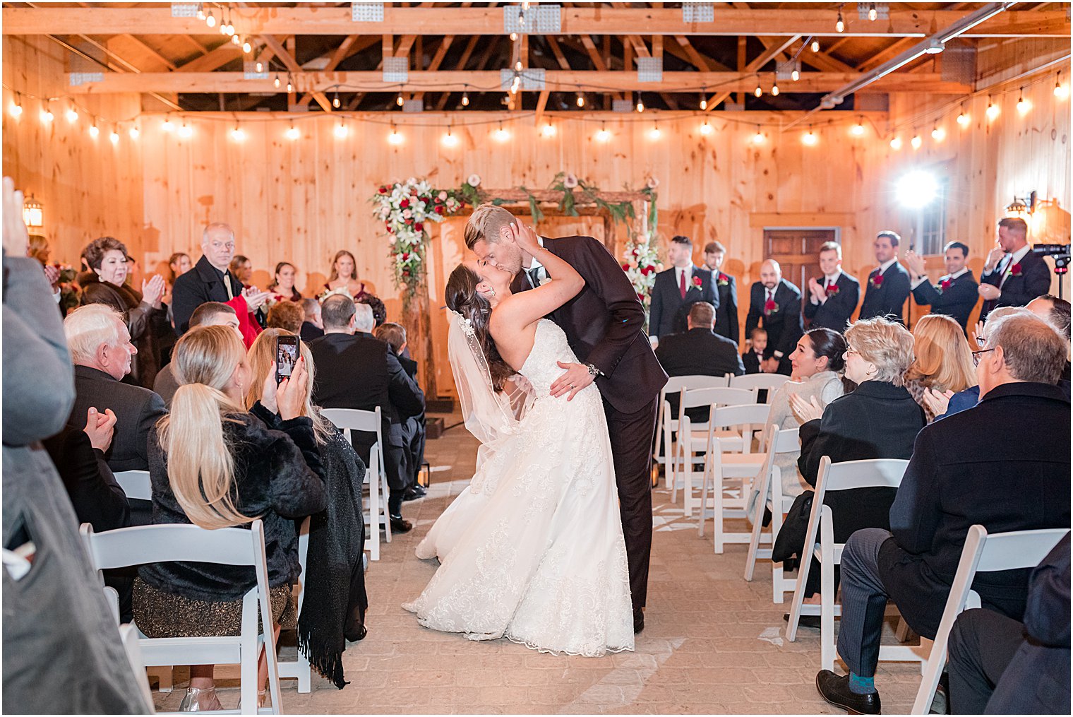 newlyweds walk up aisle and kiss after wedding ceremony in farmhouse